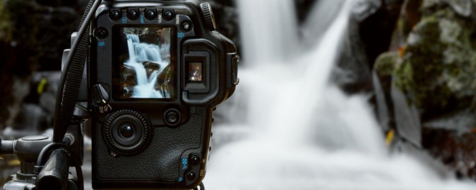 Camera on a tripod photographing a waterfall in a natural outdoor setting