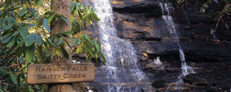 Ranger Falls waterfall at Skitty Creek beside a forest trail sign.