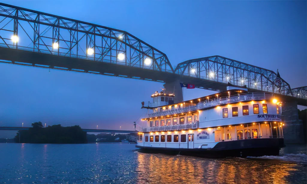 The Southern Belle riverboat gliding under a bridge lit up with lights